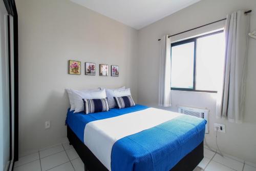 a bedroom with a blue and white bed with a window at Apartamento c/ Piscina e Garagem | CDC 3120/602 in Mossoró
