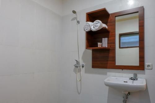 a bathroom with a shower and a sink and a mirror at Friends Beach Hotel in Kuta Lombok