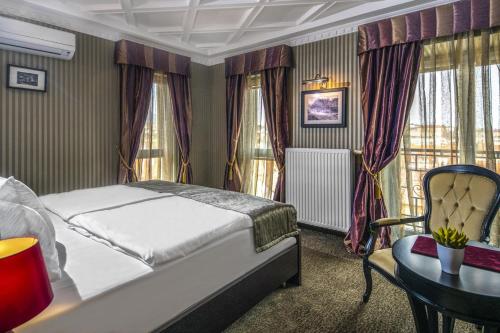 a bedroom with a bed and a table and a chair at Erla Villa Boutique Hotel in Eger