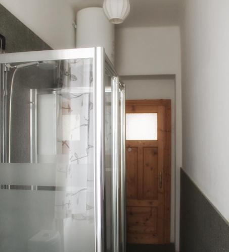 a bathroom with a shower and a wooden door at Plose Apartment in Bressanone