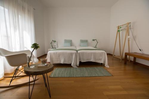 a white bedroom with a bed and a table at The Minimal House in Bombarral