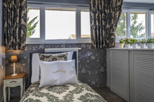 a bedroom with a bed and two windows at Erla Villa Boutique Hotel in Eger
