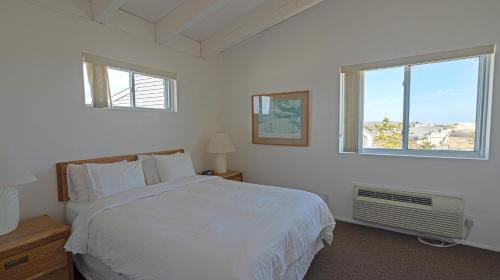 a white bedroom with a bed and two windows at Sea Crest in Amagansett
