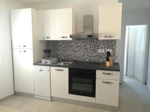 eine Küche mit weißen Schränken und einem Herd mit Backofen in der Unterkunft Apartment Seashell in Šišan