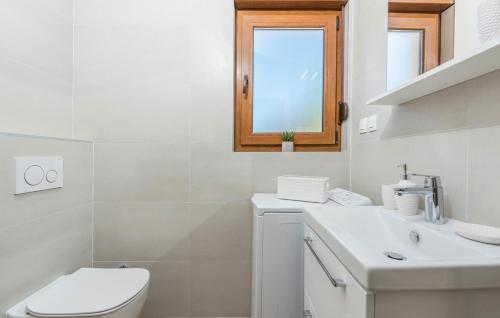 a white bathroom with a toilet and a sink at Apartments Hana in Funtana in Funtana