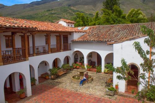 a woman standing in the courtyard of a house at Posada Portal de la Villa in Villa de Leyva