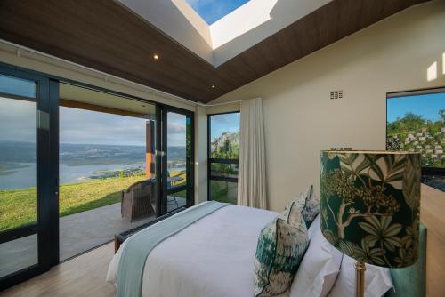 a bedroom with a bed and a large window at Alkira Lodge in Brenton-on-Sea