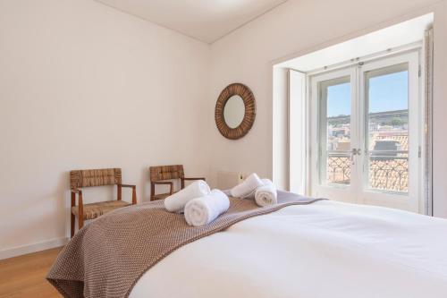 a white bedroom with a bed with towels on it at Downtown Apartment Santa Justa in Lisbon