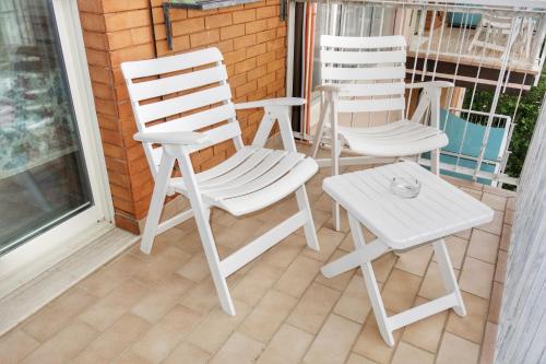 two white chairs and a table on a porch at Hotel Tridentum in Cesenatico