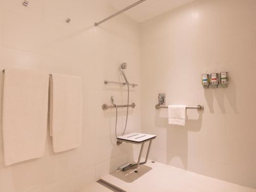 a white bathroom with a shower and towels at BTH Rebel Tacna in Tacna