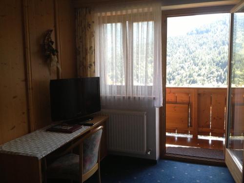 a room with a television and a large window at Berggasthof Hintergföll in Unken