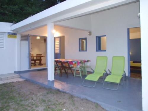 un patio con sillas verdes y una mesa en una casa en TI PARADIS DE l'ANSE FIGUIER VILLA voir site vacances en martinique, en Rivière-Pilote