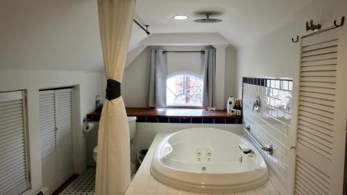 baño con una gran bañera blanca y ventana en GuestHouse, en Elizabeth