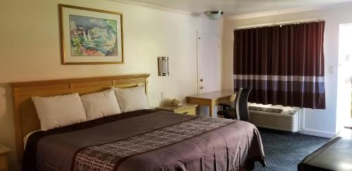 a hotel room with a bed and a desk and a window at Budget Lodge in Newport News