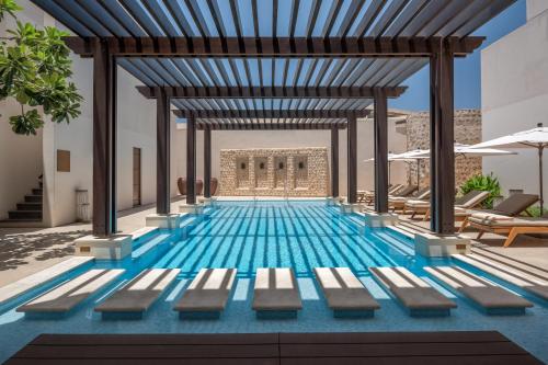 a swimming pool with benches in a building at The Chedi Al Bait, Sharjah in Sharjah