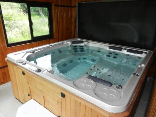 a large hot tub in a room with a window at Les Roulottes de la Risle in Calleville