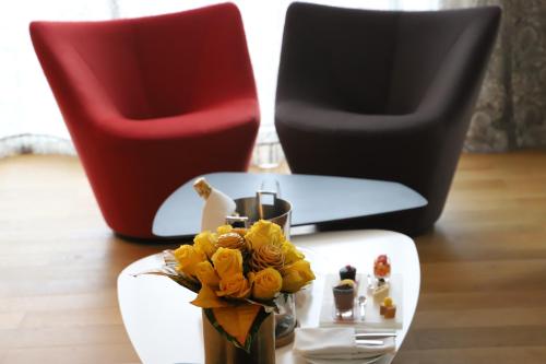 a table with a vase of flowers and two chairs at Pullman Abidjan in Abidjan