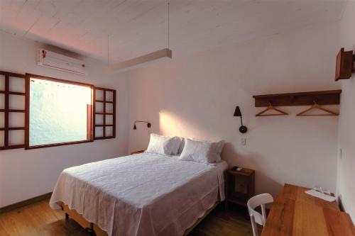 a bedroom with a bed and a table and a window at Green 53 Boutique Hotel in Ilhéus