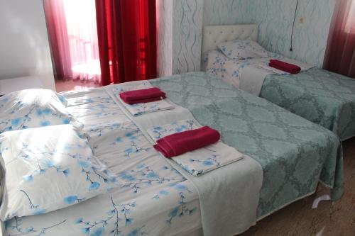 two beds with green and white sheets and red pillows at Hotel Georgia in Gonio