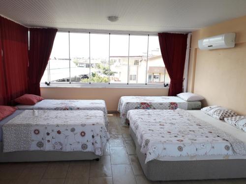 een slaapkamer met 3 bedden en een groot raam bij YALÇINKAYA PANSİYON in Burhaniye