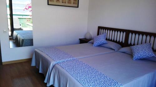 1 dormitorio con 2 camas y espejo en Ático Zeus, en Tarragona