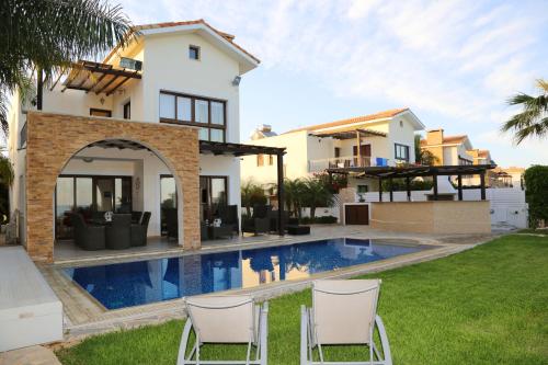 a villa with a swimming pool in front of a house at Ionion Beachfront Villa in Ayia Napa