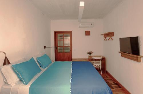 a bedroom with a blue bed and a tv at Green 53 Boutique Hotel in Ilhéus