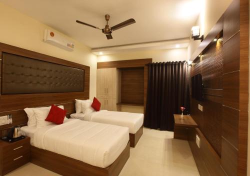 a hotel room with two beds and a television at Laimar Suites in Cochin