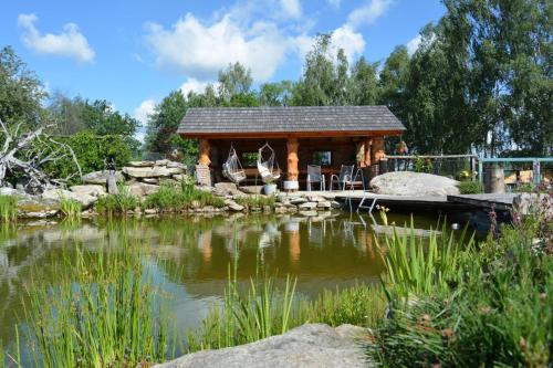 a log cabin next to a pond in a garden at Ekofarma Horní Chrášťany in Lhenice