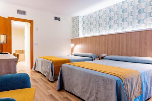 a hotel room with two beds and a chair at Peñiscola Plaza Suites in Peniscola