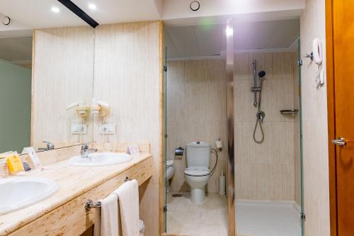 
a bathroom with a toilet, sink, and shower at Peñiscola Plaza Suites in Peniscola
