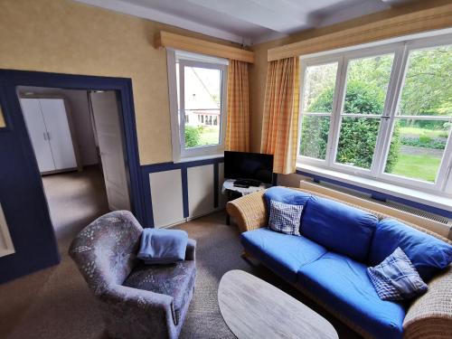 a living room with a blue couch and a chair at Ferienhof Ehlers in Hülsede