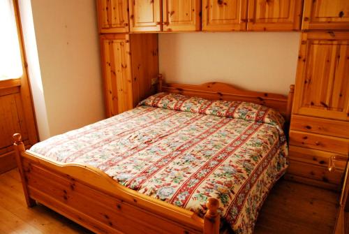 a bedroom with a bed with a wooden frame and cabinets at Pejo Appartamenti Pegolotti in Cogolo