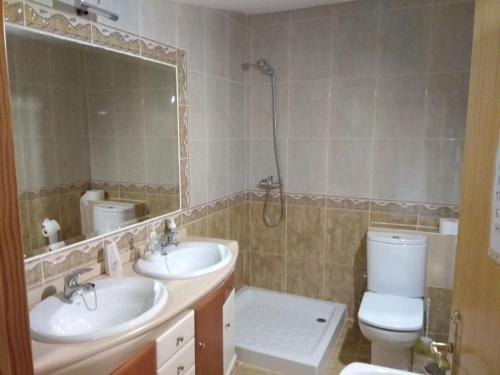 un bagno con due lavandini, un water e uno specchio di Villa el Gallo a Los Cortijos