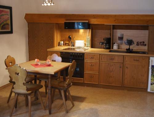 a kitchen with a wooden table and a table and chairs at Pension Loni Theisen in Kelberg