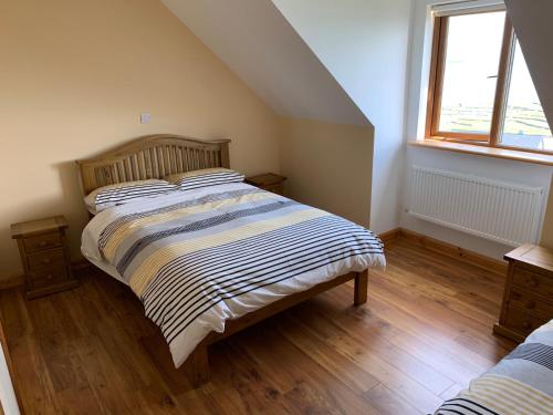 a bedroom with a bed with a striped comforter and a window at Cliffs of Moher View in Inisheer