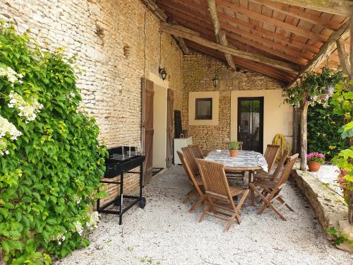 un patio avec une table et des chaises et un mur de briques dans l'établissement BelBiarge, à Chaunay