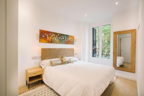 a white bedroom with a bed and a mirror at PRIM 26 in Donostia-San Sebastián
