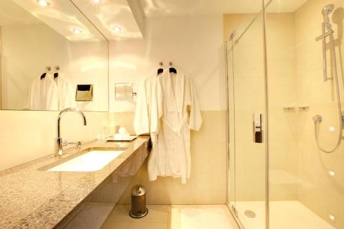 a white bathroom with a sink and a shower at Hotel Favor in Düsseldorf