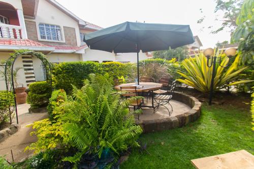 a table and chairs with an umbrella in a garden at Zarita Boutique Hotel in Nairobi