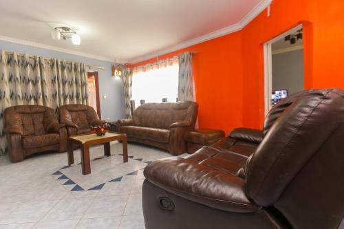 a living room with leather furniture and an orange wall at Zarita Boutique Hotel in Nairobi
