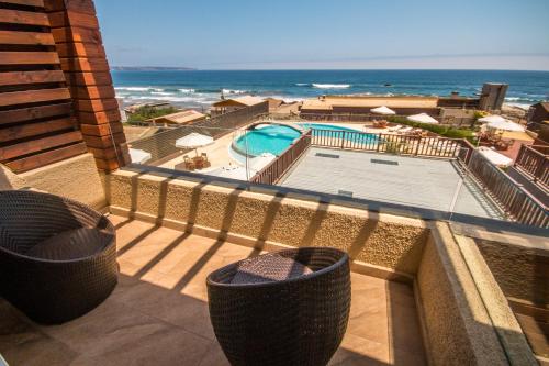 a balcony with a view of a swimming pool and the ocean at Hotel Mae in Maitencillo