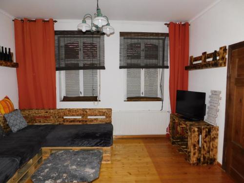 a living room with red curtains and a tv at Haus Feierabend in Plodda