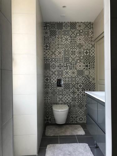 a bathroom with a toilet and a tile wall at Les Chambres d'Hotes chez Alisa et Daniel in Sarlat-la-Canéda