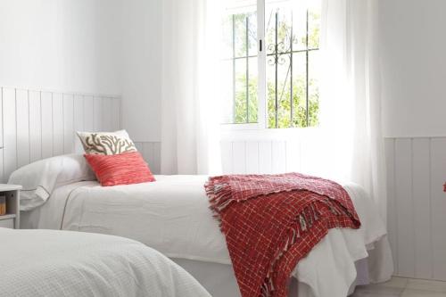 卡拉德米哈斯的住宿－Los Geranios - Beach Apartment，一间卧室配有两张带红色枕头的床和窗户。