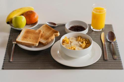 a breakfast table with a bowl of cereal and toast at Hotel Palapa Palace in Tuxtla Gutiérrez