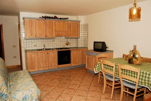a kitchen with wooden cabinets and a table with chairs at Pejo Appartamenti Pegolotti in Cogolo
