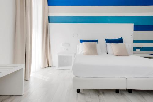 a bedroom with a white bed and a blue and white wall at Marina di Petrolo Hotel & SPA in Castellammare del Golfo