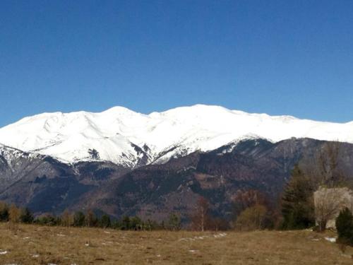 a snow covered mountain in front of a field at Casa Rural Mollo, Vall de Camprodon in Molló