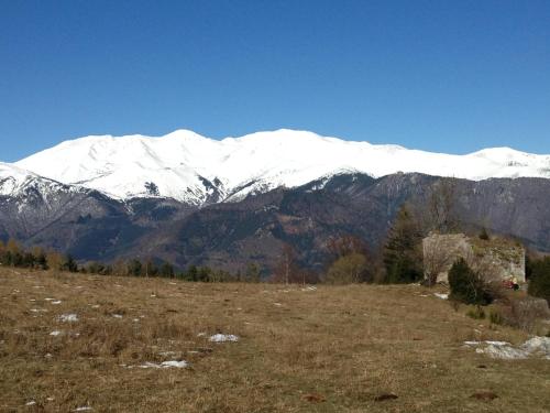 a snow covered mountain in a field with a house at Casa Rural Mollo, Vall de Camprodon in Molló